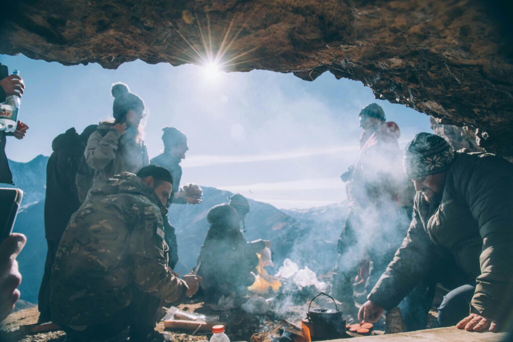 pexels-photo-8581301-8581301 A group of adults enjoy camping and cooking in a cave amidst the mountains under sunlight.